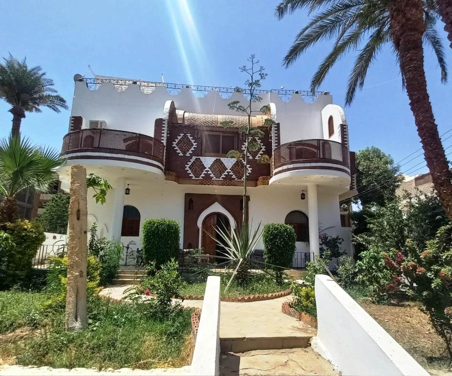 una gran casa blanca con una palmera en Villa Giulio Luxor Guest House en Luxor
