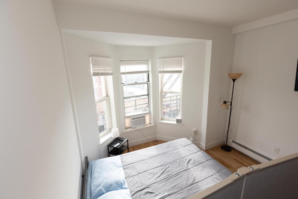 ein weißes Zimmer mit einem Bett in einem Zimmer mit Fenstern in der Unterkunft Deluxe Studio Apt Close to NYC in Union City