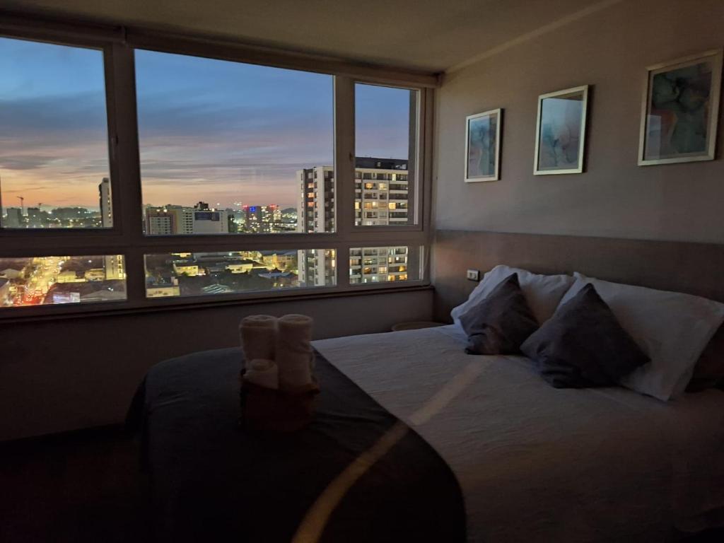 a bedroom with a bed with a view of a city at NM ApartHotel Tucapel in Concepción