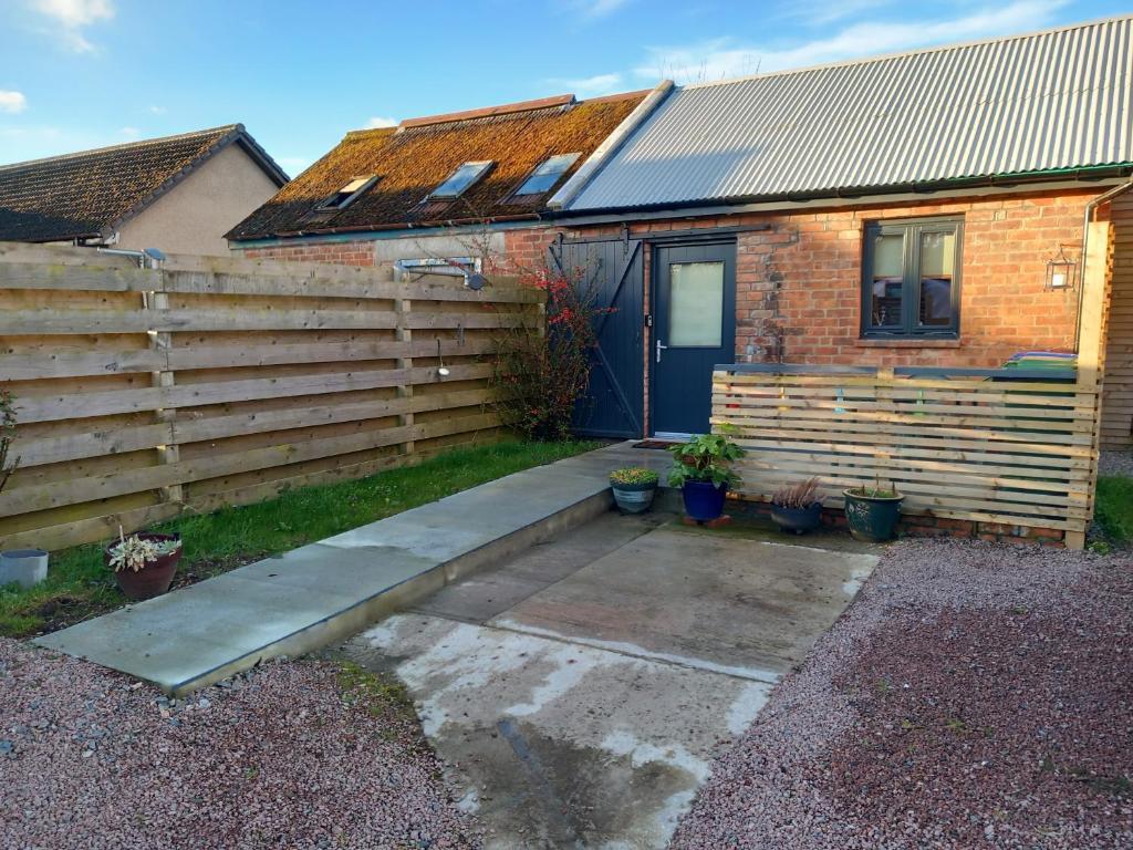 a house with a wooden fence and a driveway at The Coo Shed in Inverness
