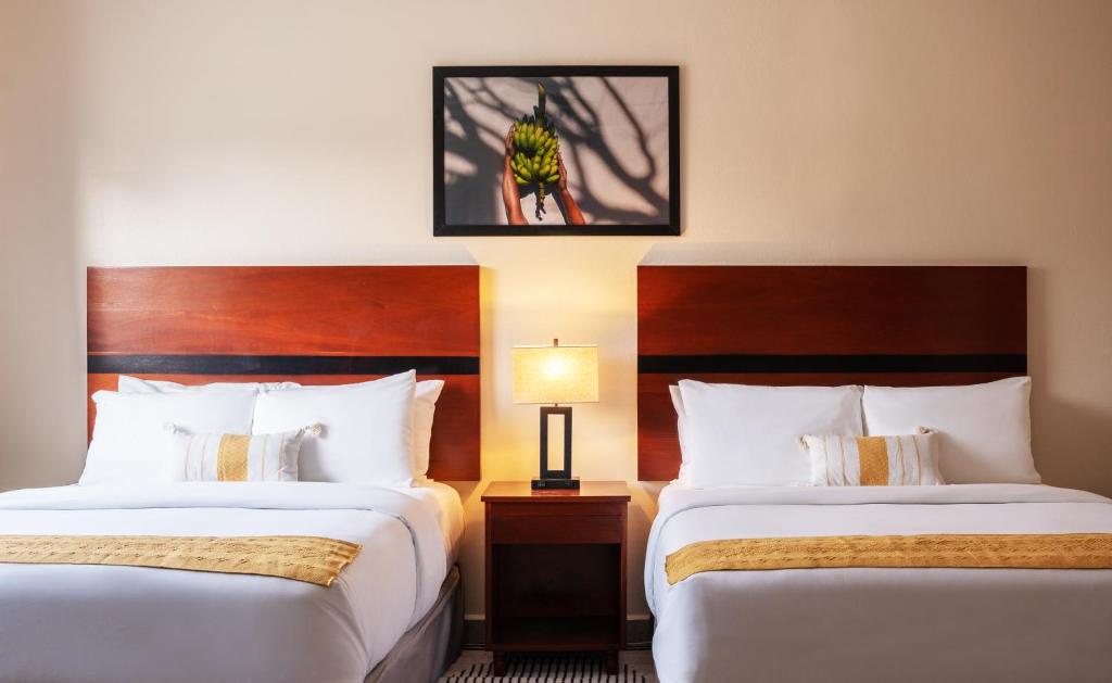 ein Hotelzimmer mit 2 Betten und einem Bild an der Wand in der Unterkunft The West House Boutique Hotel in San Ignacio