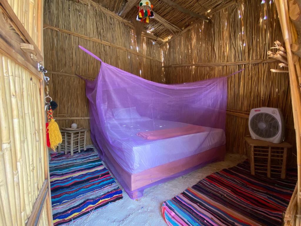 a bedroom with a purple bed in a wooden hut at Paloma Camp in Siwa