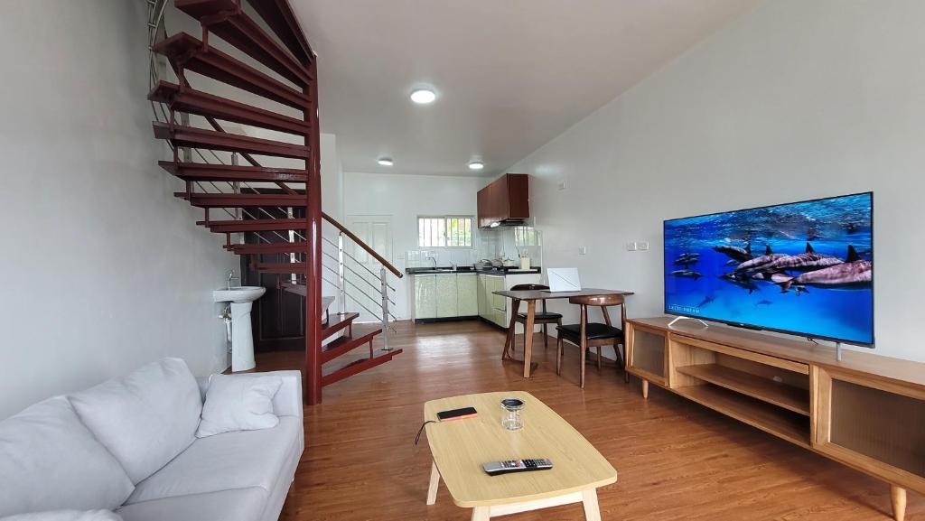 sala de estar con sofá blanco y TV de pantalla grande en Easy Apt en Suva
