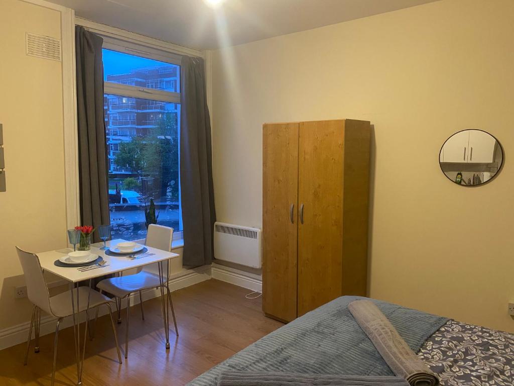 a bedroom with a bed and a table and a window at Studio flat/Close to central in Hendon
