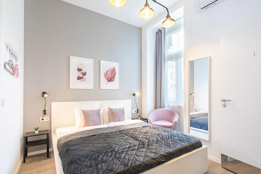 ein Schlafzimmer mit einem Bett und einem rosa Stuhl in der Unterkunft Extreme Central - Modern Mini Studio in Budapest