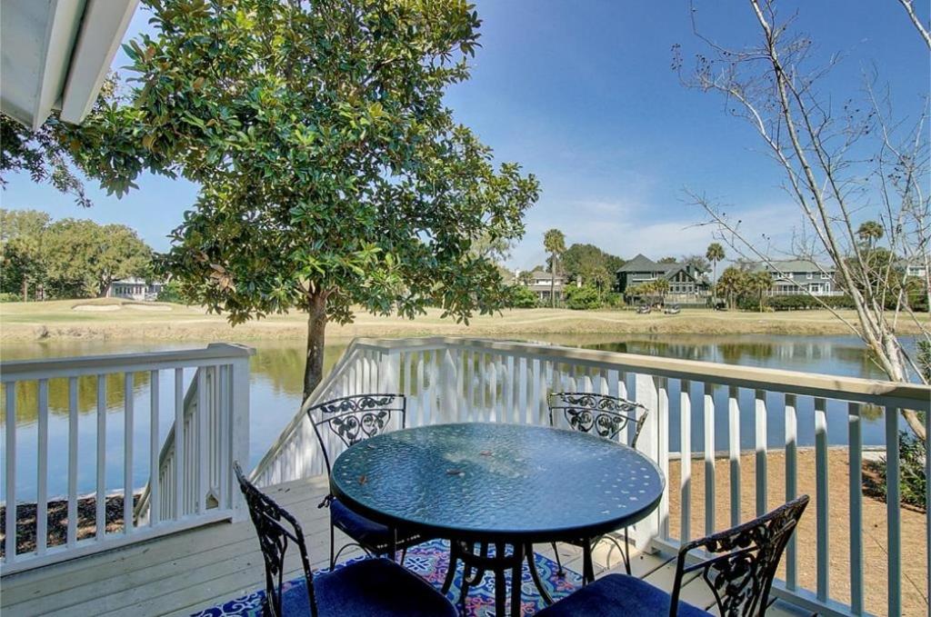 a table and chairs on a porch with a view of the water at 15 Lake Village by AvantStay Golf Course Lagoon Views in Isle of Palms