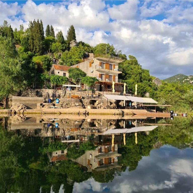 a house on a hill with a reflection in the water at Sunny Terraces in Cetinje