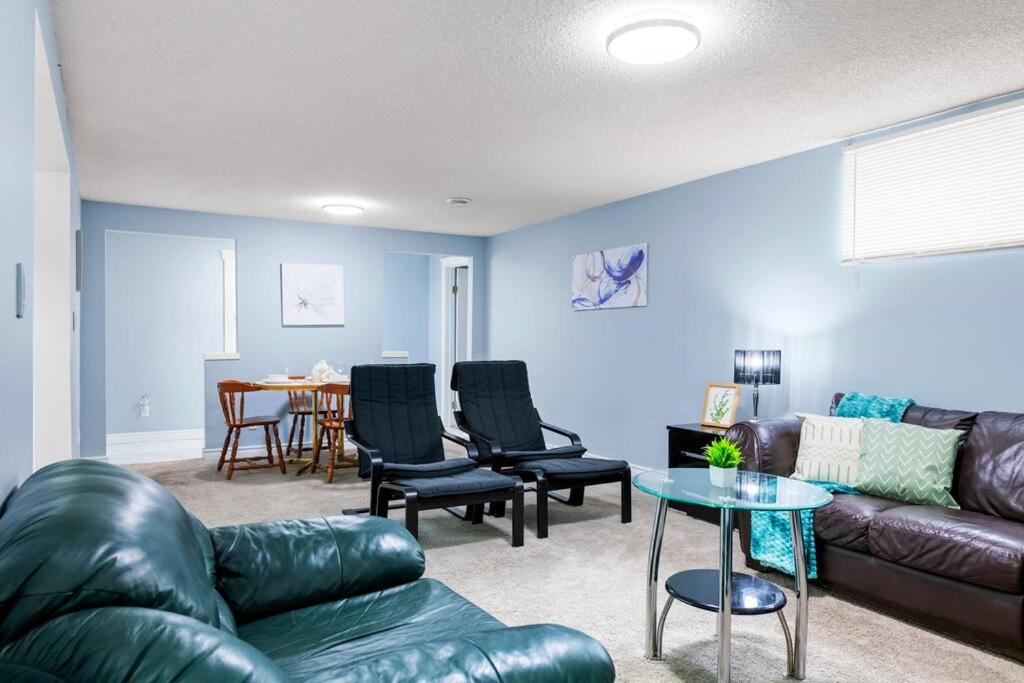 a living room with a leather couch and chairs and a table at Cozy Suite - Walk to West Ed Mall in Edmonton