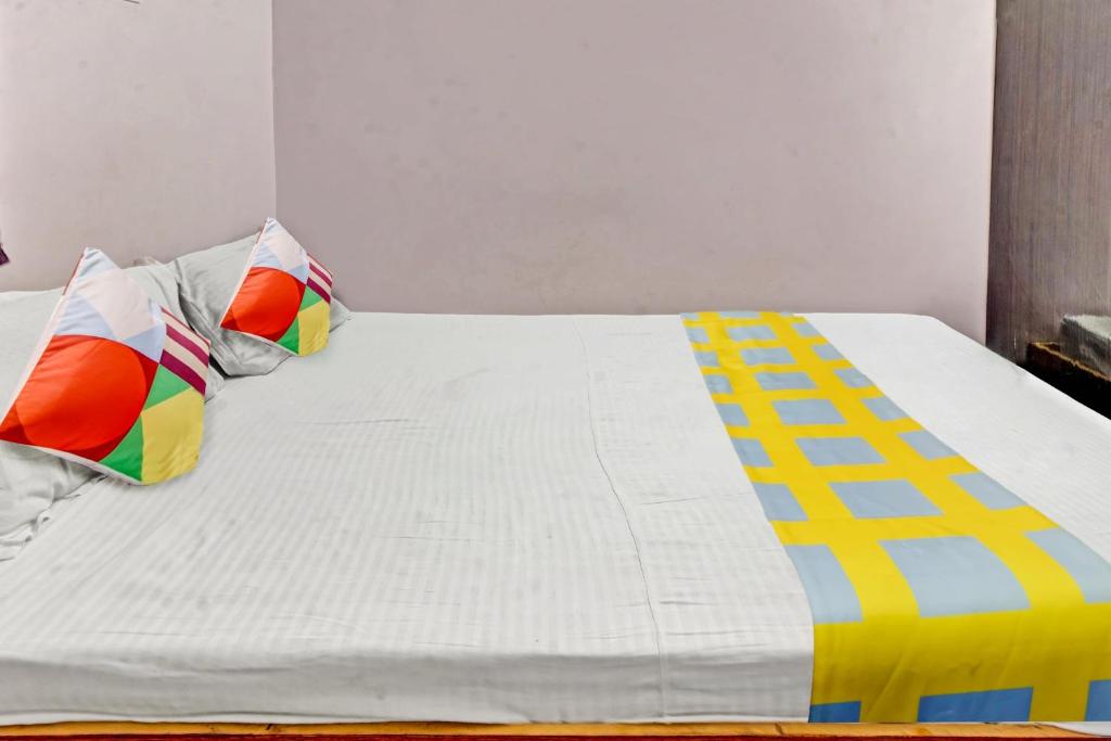 a white bed with colorful pillows on top of it at Super OYO Hotel Happy Inn in Patna