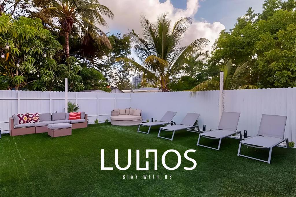 a lawn with chairs and a fence with the words lobos at Modern Miami Home 10 Min to the AIRPORT L03 in Miami