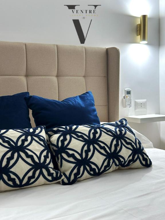 a bed with a black and white blanket and blue pillows at Ventre luxury rooms in Naples