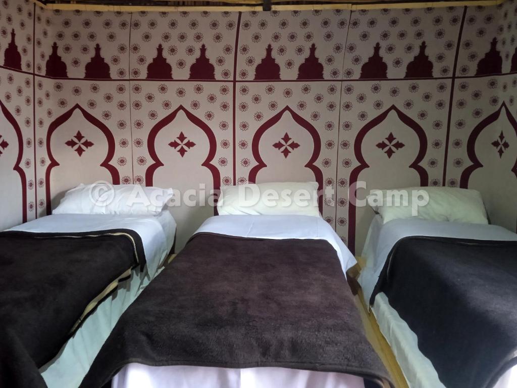 two beds in a room with red and white wallpaper at Acacia Desert Camp in Merzouga