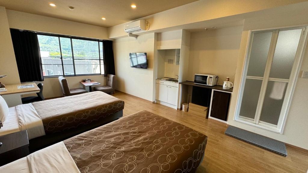 a hotel room with two beds and a kitchen at Yufuin Akarinoyado in Yufuin