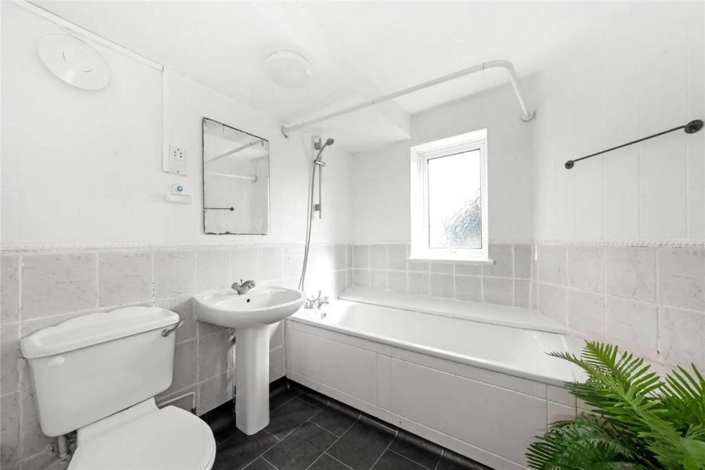 La salle de bains blanche est pourvue de toilettes et d'un lavabo. dans l'établissement Homestay CR7, à Thornton Heath