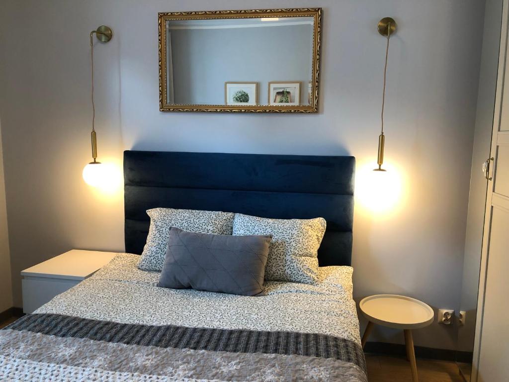 a bedroom with a bed with a blue headboard and a mirror at Amber in Gdańsk