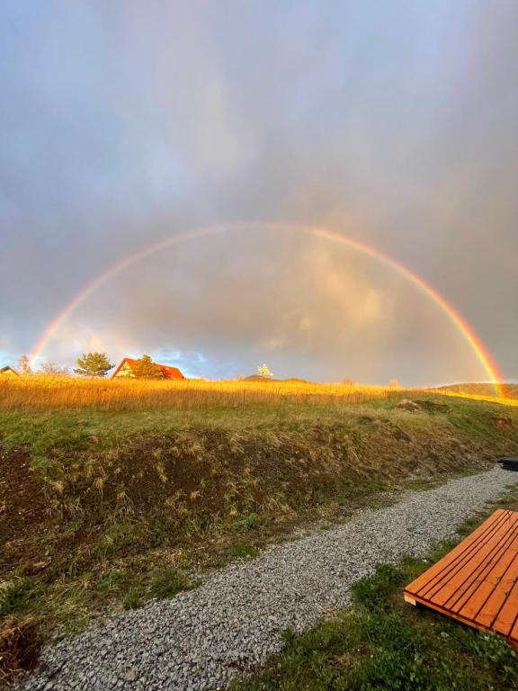 a rainbow in the sky over a field at Sunny Houses domki rekreacyjne in Sobótka