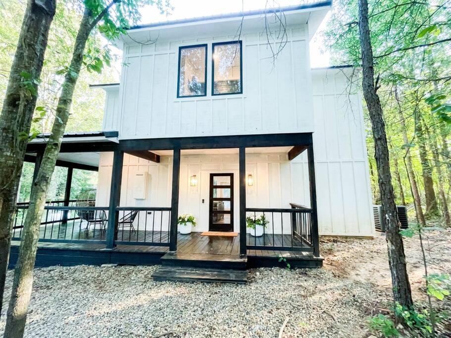 a white house with a front door in the woods at the RISER - BRAND NEW Modern Cabin in Broken Bow in Broken Bow