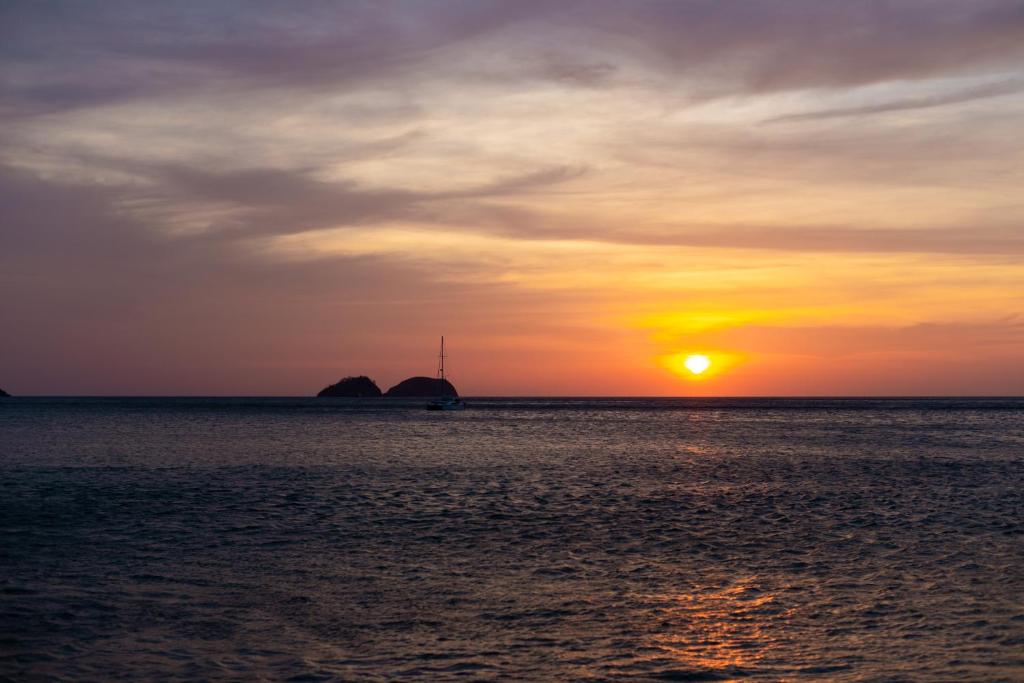 een zonsondergang over de oceaan met een boot in het water bij Sunset Harmony, Your Escape at Playa Hermosa in Sardinal