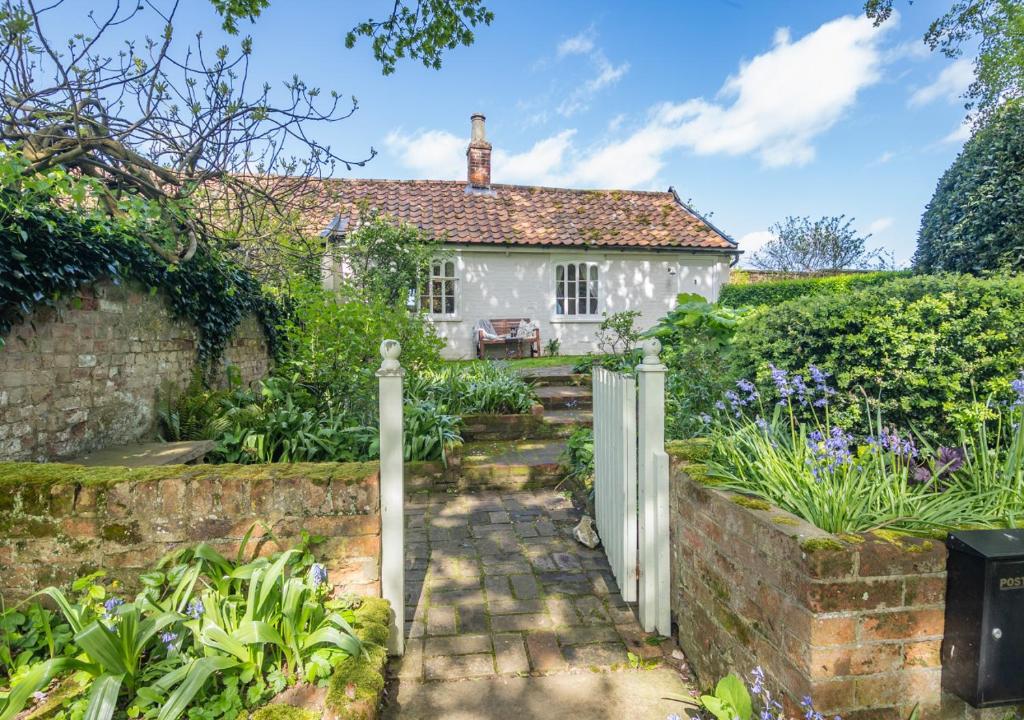 une maison blanche avec un jardin et une clôture dans l'établissement Gardeners Cottage, à Bealings