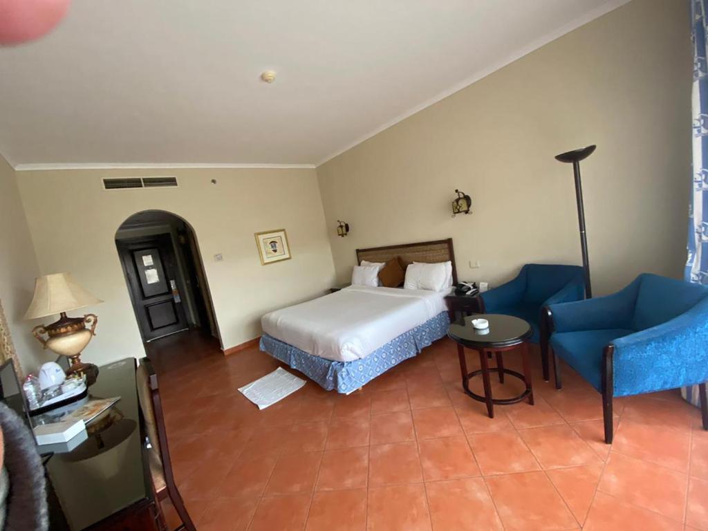 een hotelkamer met een bed en een blauwe stoel bij INGOING Marina in El Alamein