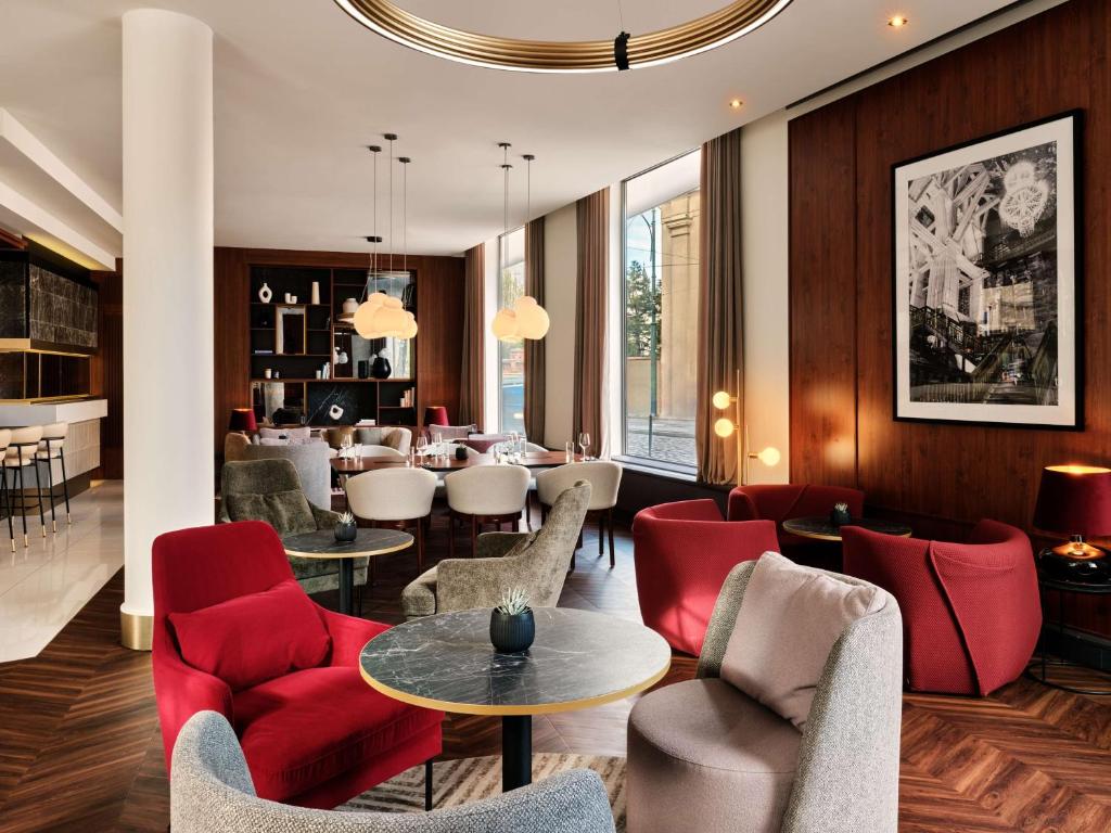 a hotel lobby with red chairs and a dining room at Radisson Blu Hotel Krakow in Kraków