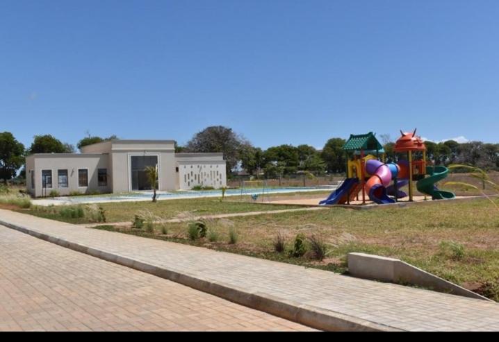 Vipingo Nomadic Apartment في Tezo: حديقة بها ملعب مع معدات للعب الأطفال