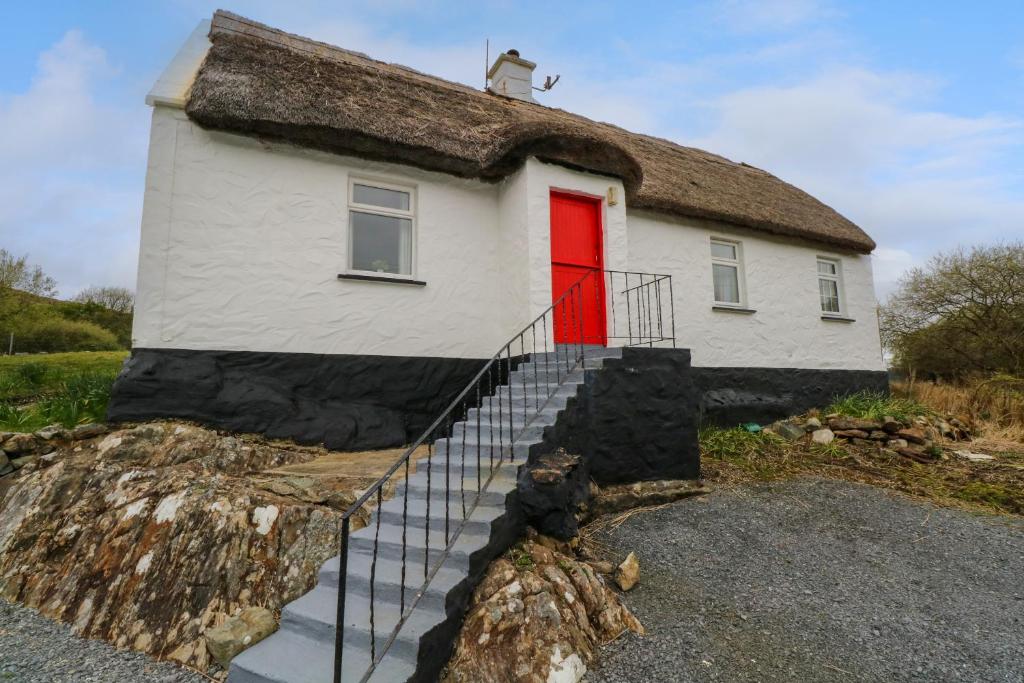 una casa con techo de paja y puerta roja en Aggrafard, en Glentrasna