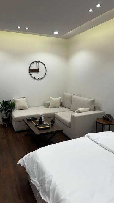 استديو العقيق في الرياض: غرفة معيشة مع أريكة وساعة على الحائط