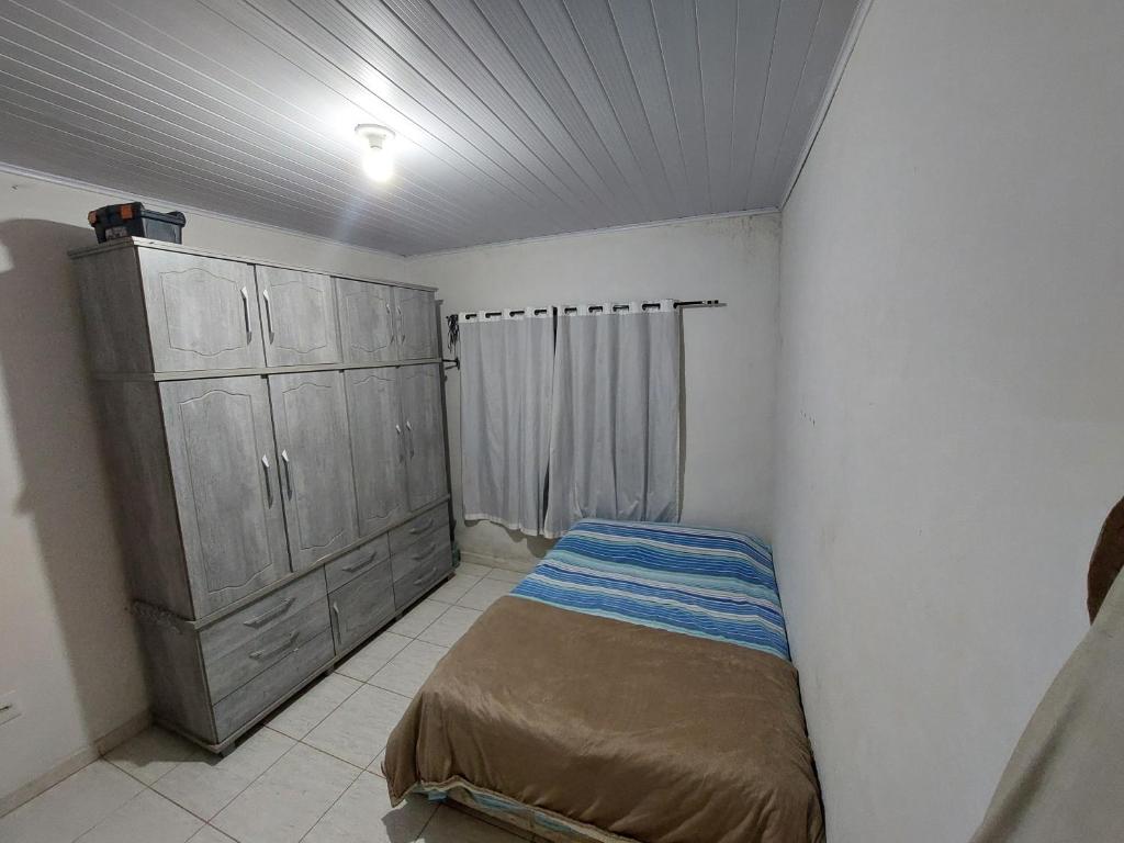 a small bedroom with a bed and a cabinet at Temporada para Agrishow in Ribeirão Preto