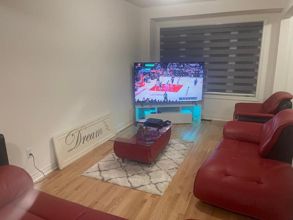 sala de estar con TV de pantalla plana y sofás rojos en Comfort Queen, en Oshawa
