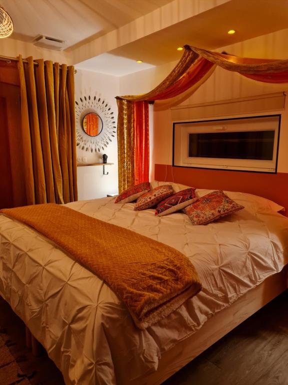 a bedroom with a large bed with red curtains at Home Gãyatri in Angé