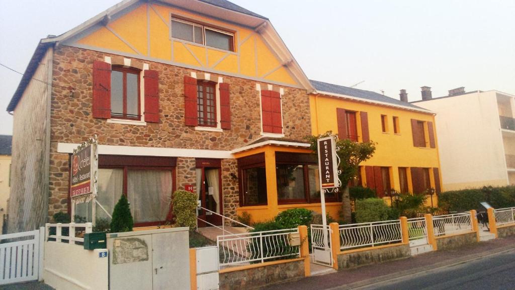 ein gelbes und rotes Haus mit einem Schild davor in der Unterkunft Le Richelieu in Saint-Jean-de-Monts