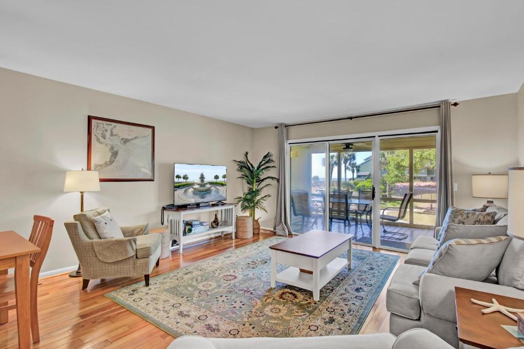 uma sala de estar com um sofá e uma mesa em 3C Mariners Walk by AvantStay Beach Pool Access Enclosed Porch em Isle of Palms