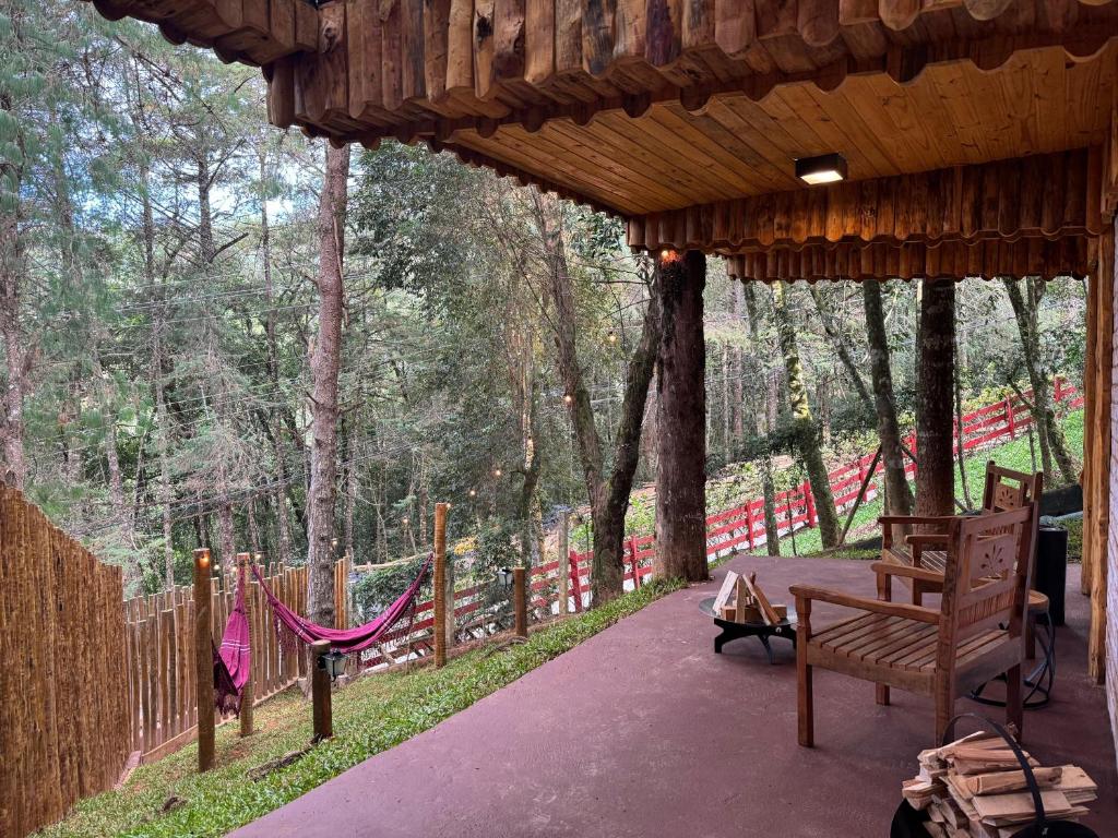 a porch with a hammock and a fence at Estalagem Serra de Minas em Monte Verde in Monte Verde