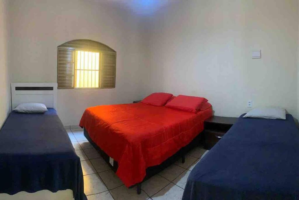 1 dormitorio con 2 camas y manta roja en Casa de Férias 1purbana en Ribeirão Preto