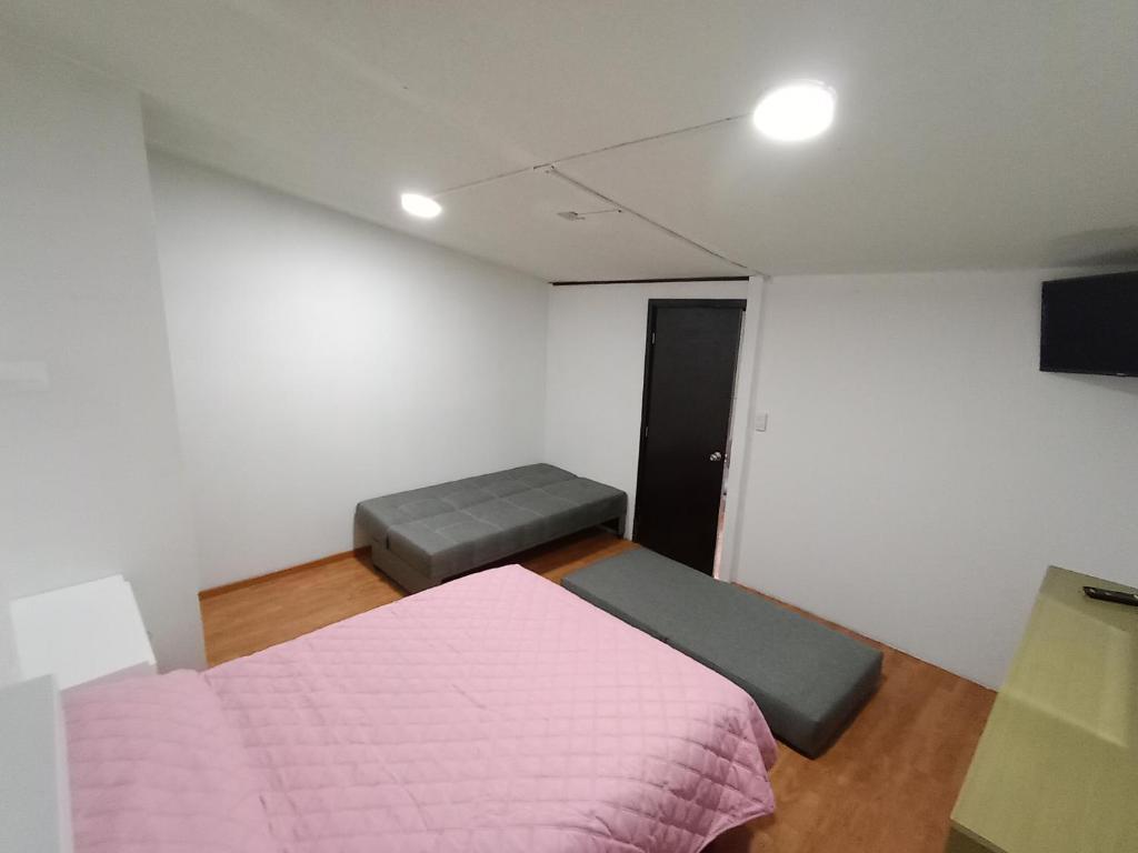 1 dormitorio con cama rosa y sofá en Loft Santa rosa, en Apizaco