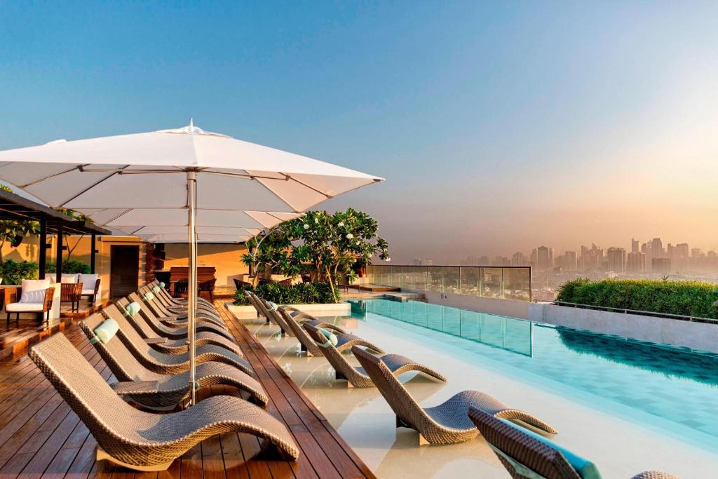 a pool with chairs and an umbrella with a view at Manila Marriott Hotel in Manila