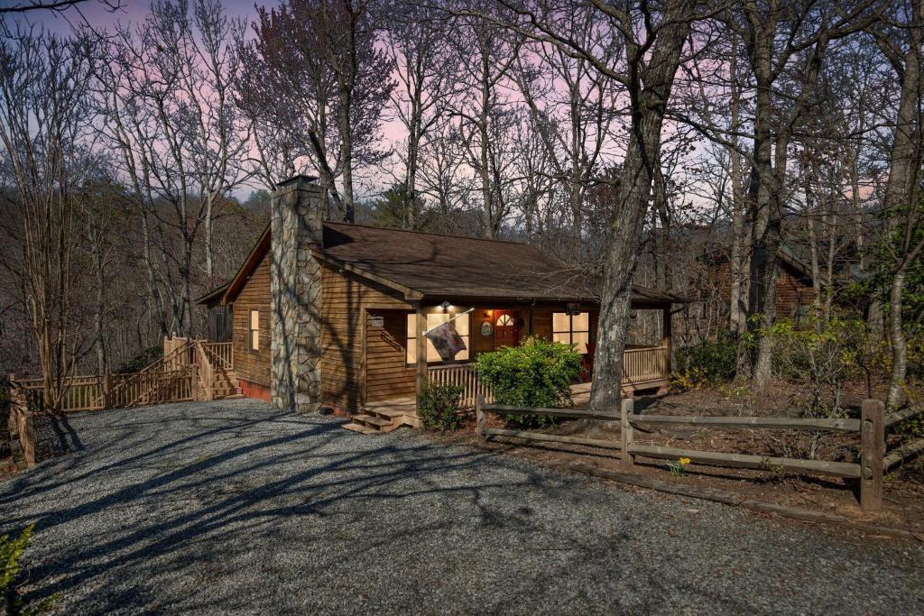 una cabaña de madera en el bosque con una valla en A Cozy 2BR Log Cabin Getaway-Mirror Lake-Fireplace cabin, en Lake Lure