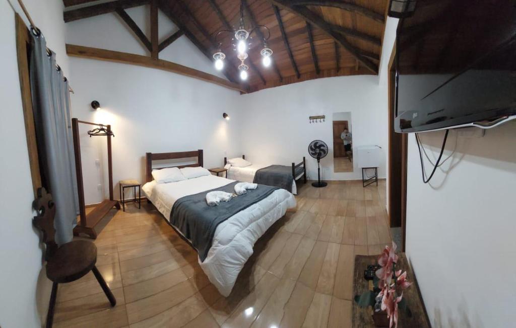 a bedroom with a bed and a flat screen tv at Suítes Encanto de Minas in Tiradentes