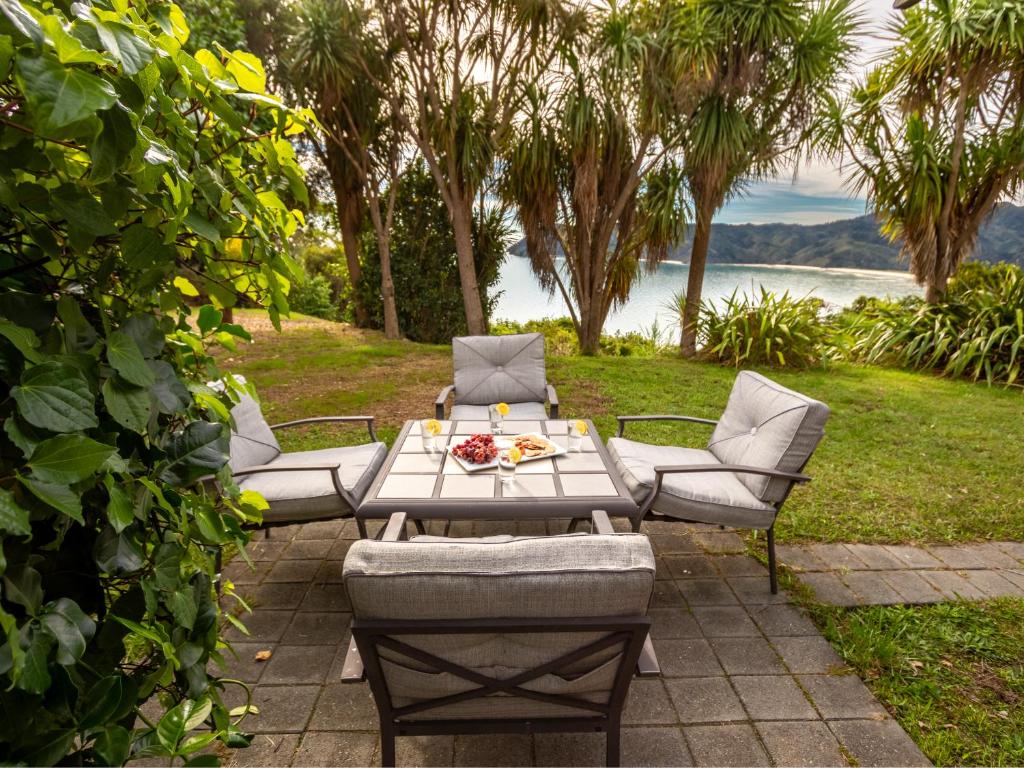 a picnic table and chairs with a view of the water at The Gatehouse - Takaka Holiday Home in Takaka