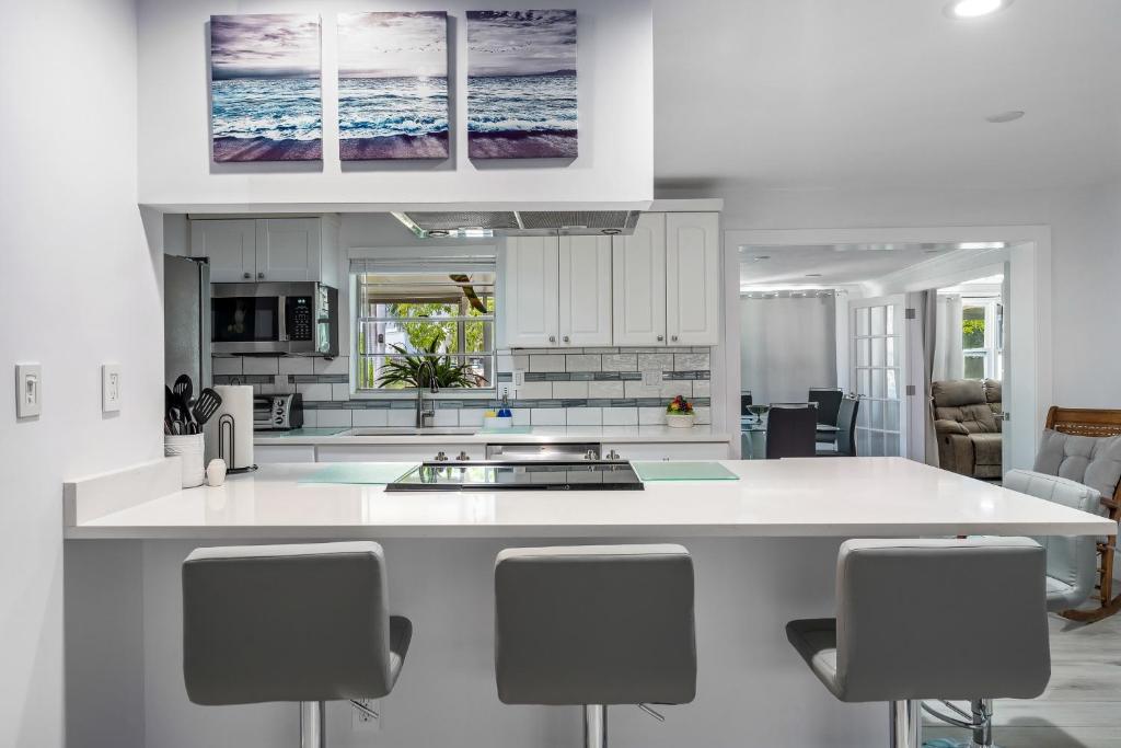 a kitchen with white cabinets and a island with bar stools at Secluded Family Serenity on Canal with 2 Bikes and Beach Chairs in Naples