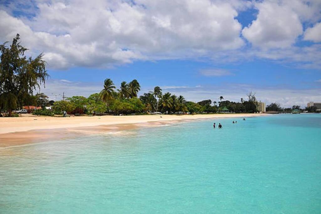 a beach with people swimming in the water at Beach Life Villa in Bridgetown
