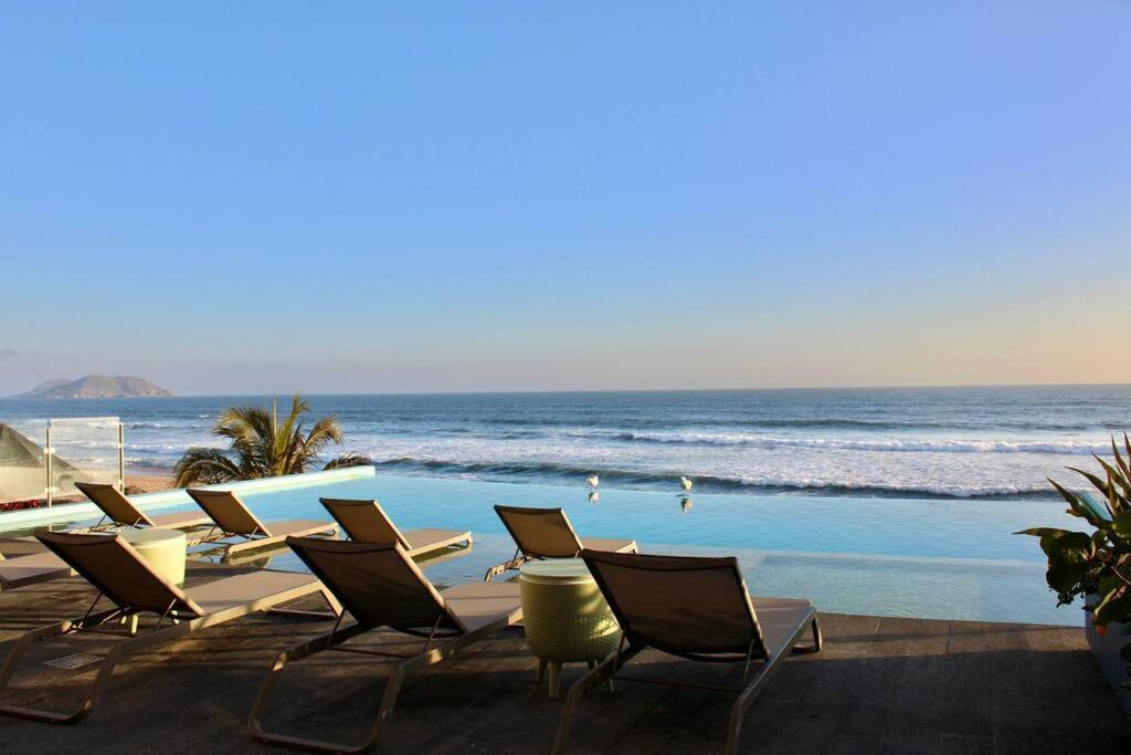 un grupo de sillas y una piscina con el océano en Brujas Tower- Hermoso departamento a pie de playa., en La Florida