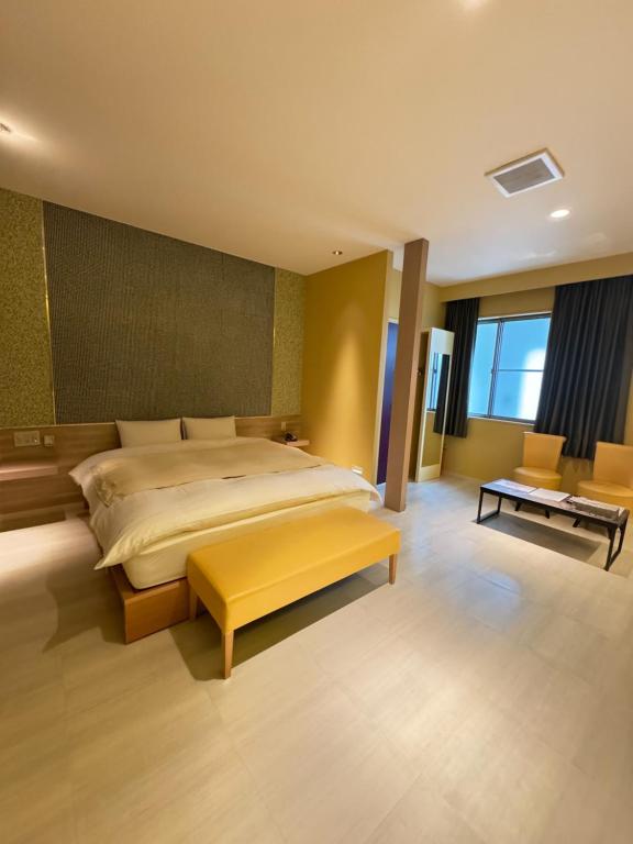 um quarto com uma cama grande e um banco amarelo em Hotel JOYCE em Saijō-chō