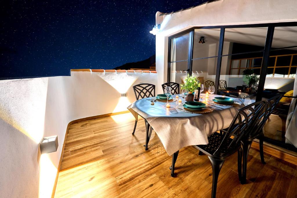 una mesa y sillas en un balcón por la noche en El Mirador, en Zuheros