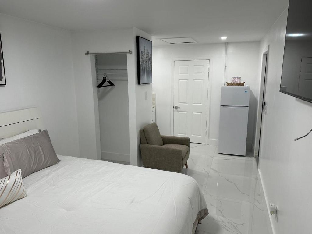 a bedroom with a bed and a chair and a refrigerator at Adrien Guest Studio in Miami Gardens