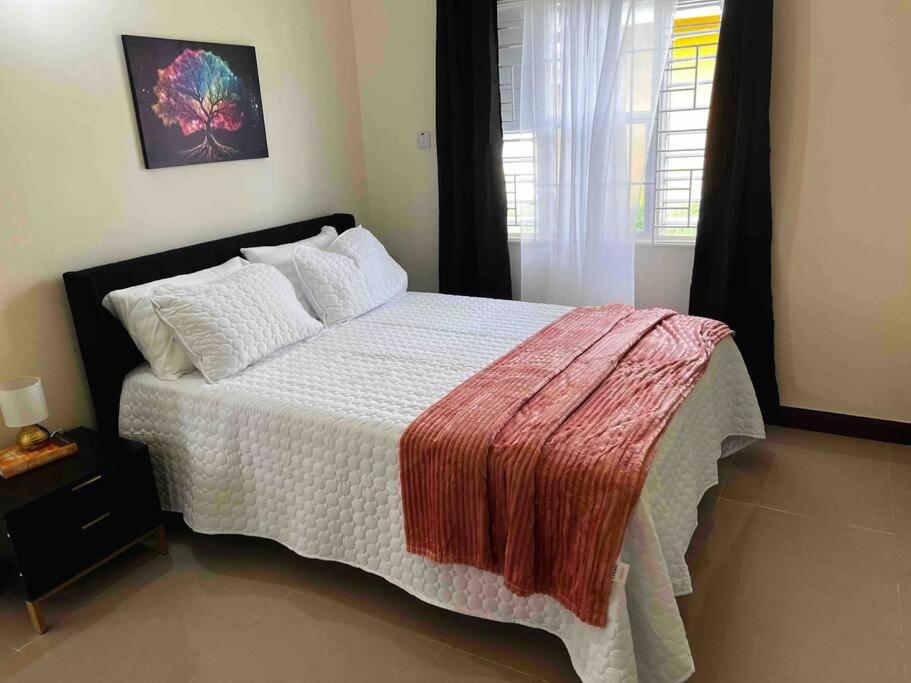 a bedroom with a bed with a red blanket on it at BellaRose at Colbeck ,Gated with Pool, Stylishly modern in Old Harbour