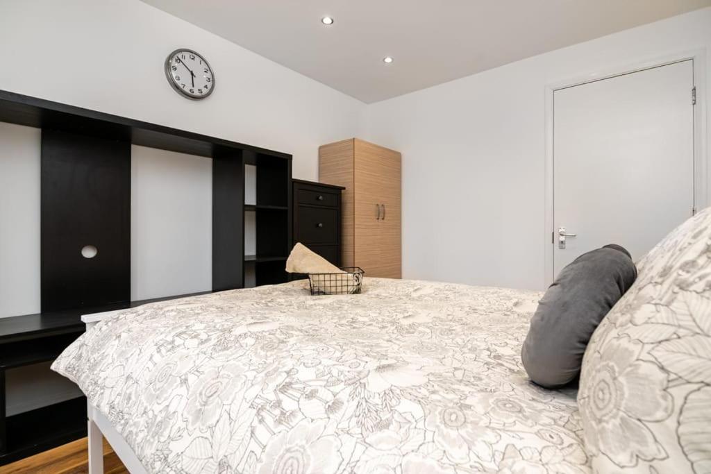1 dormitorio con 1 cama con reloj en la pared en Modern House Just Refurbished, en Londres