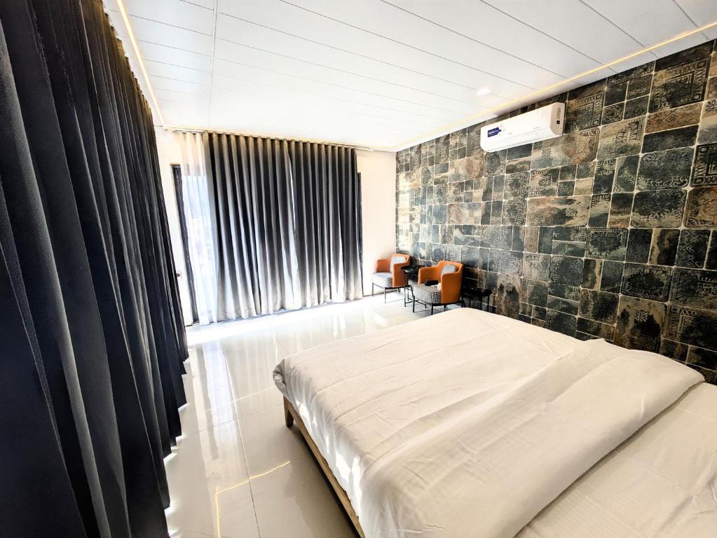 1 dormitorio con cama y pared de piedra en The Retro Glass House, en Mount Abu