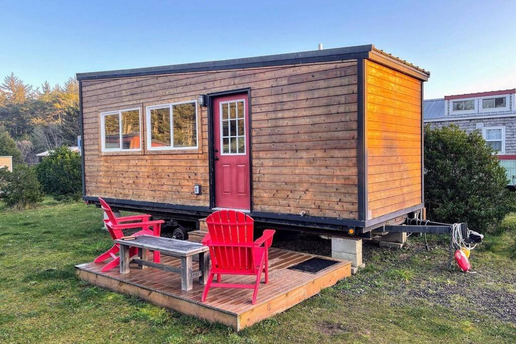 a tiny house with two red chairs and a table at Shorepine - Tiny Tranquility on the Oregon Coast! in Waldport